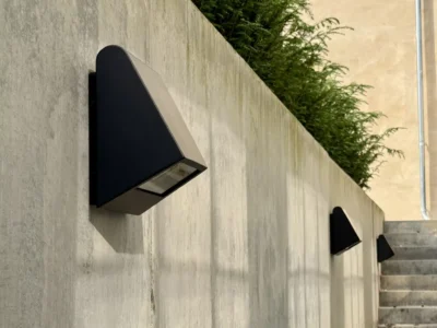 Moderne væglampe på betonvæg med planter.