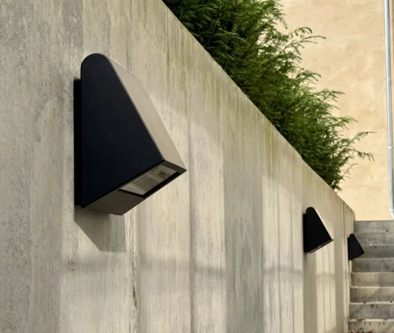 Moderne væglampe på betonvæg med planter.