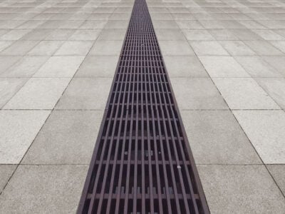 Ziegelsteinpflaster mit einem langen Metallgitter.