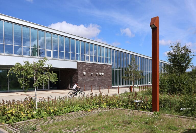 Cyklist foran moderne bygning med glasfacade.