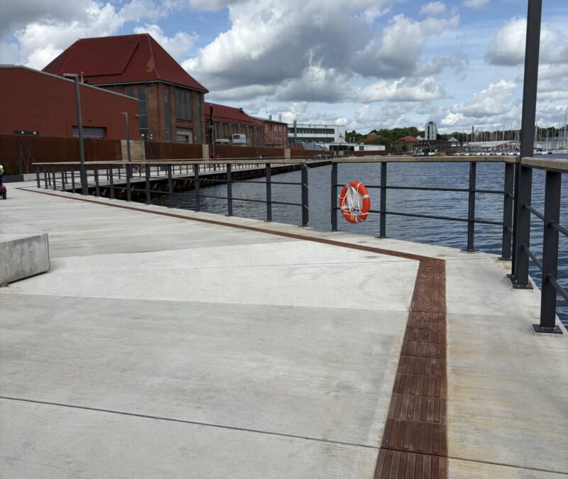Havnepromenade med livredderbøje og skyer