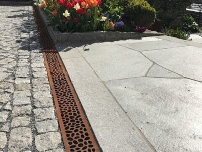 Blomsterbed med tulipaner ved pavérbelægning.