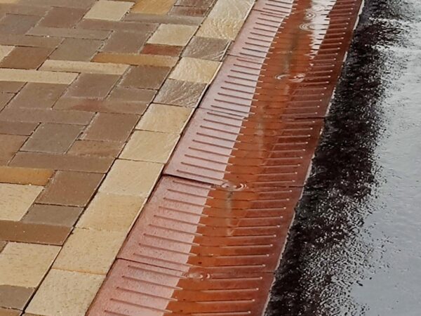 Wet pavement with stones and drainage gutter
