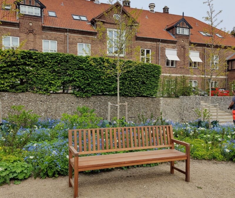 Bænk i en have med blomsterbed.