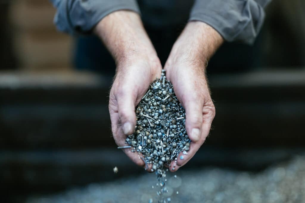 Hænder holder metalstænger og skruer.