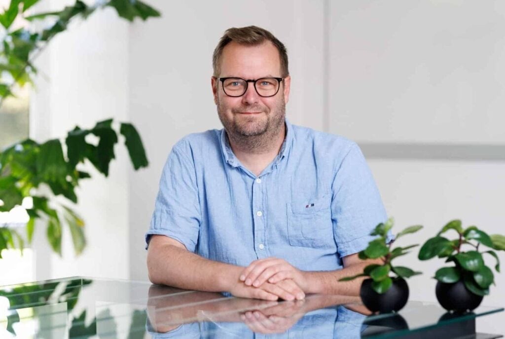 Man sitter vid skrivbord med växter