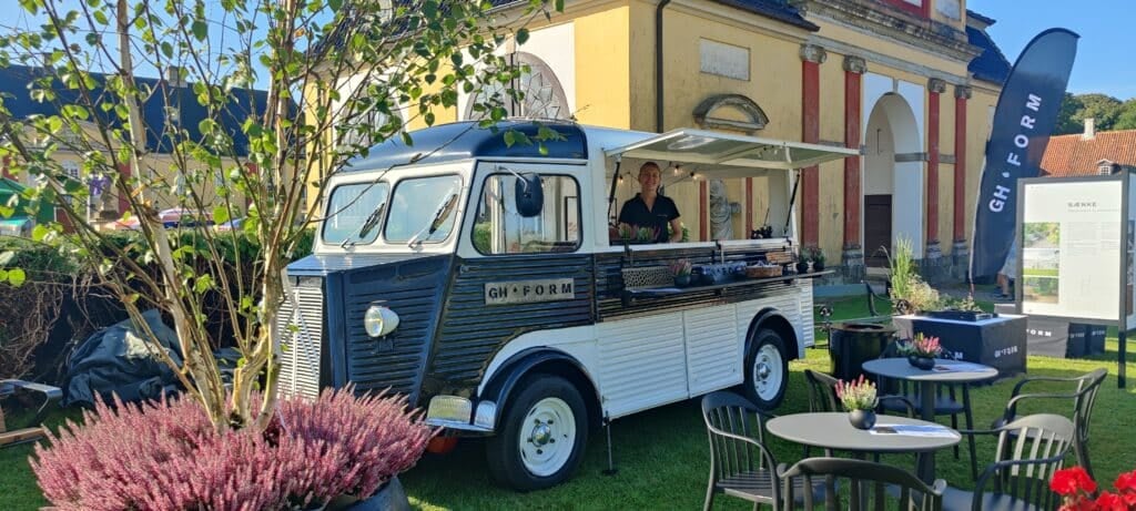 Essenswagen in einem sonnigen Außenbereich mit Tischen.