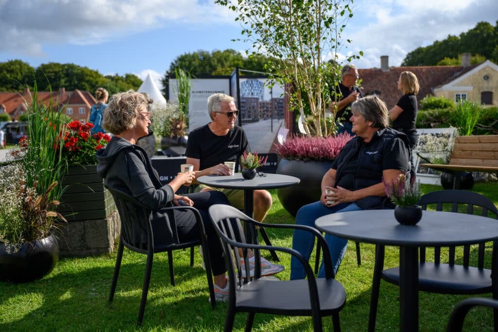 Drei Personen, die sich im Freien ungezwungen unterhalten.